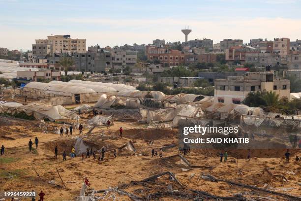 People stand around craters caused by Israeli bombardment in Rafah on the southern Gaza Strip on February 12 amid ongoing battles between Israel and...