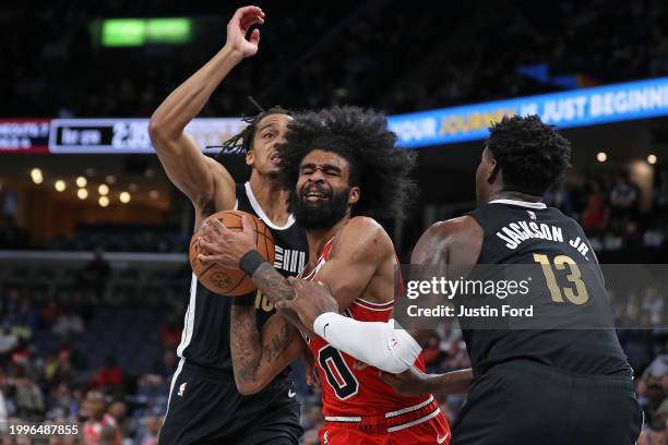 Coby White of the Chicago Bulls goes to the basket between Jaren Jackson Jr. #13 of the Memphis Grizzlies and Tosan Evbuomwan of the Memphis...