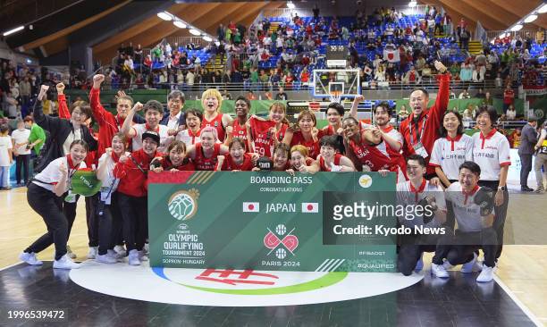 Members of the Japanese women's basketball team pose for photos after the team secured a spot in the 2024 Paris Olympics by defeating Canada in a...