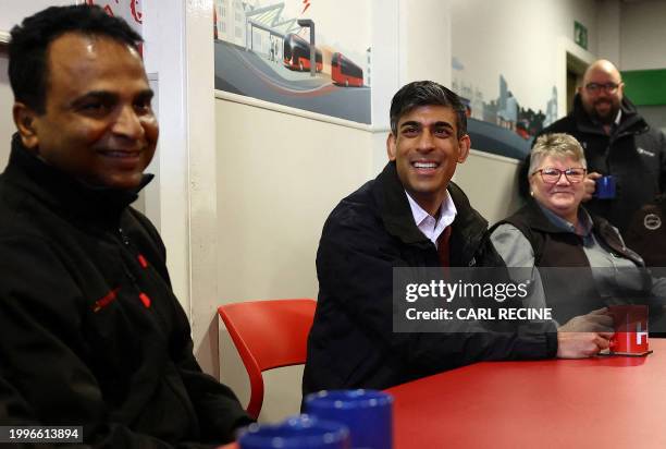 Britain's Prime Minister Rishi Sunak reacts as he talks with bus drivers during a visit to a bus depot in Harrogate, northern England on February 12,...