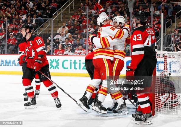 Jakob Pelletier reacts with Kevin Rooney of the Calgary Flames after Rooney's goal during the third period as Ondrej Palat and Luke Hughes of the New...