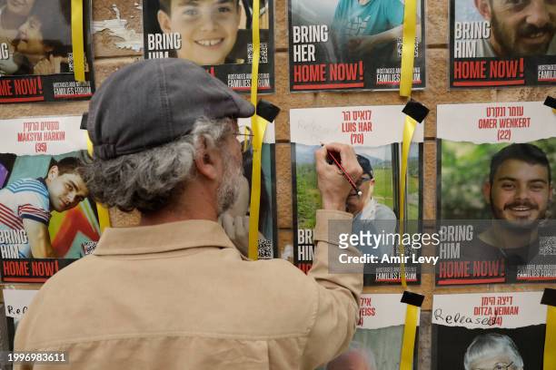 Man writes released and rescued on a poster of missing Israeli, Louis Har on a wall at Hostages Square on February 12, 2024 in Tel Aviv, Israel. The...
