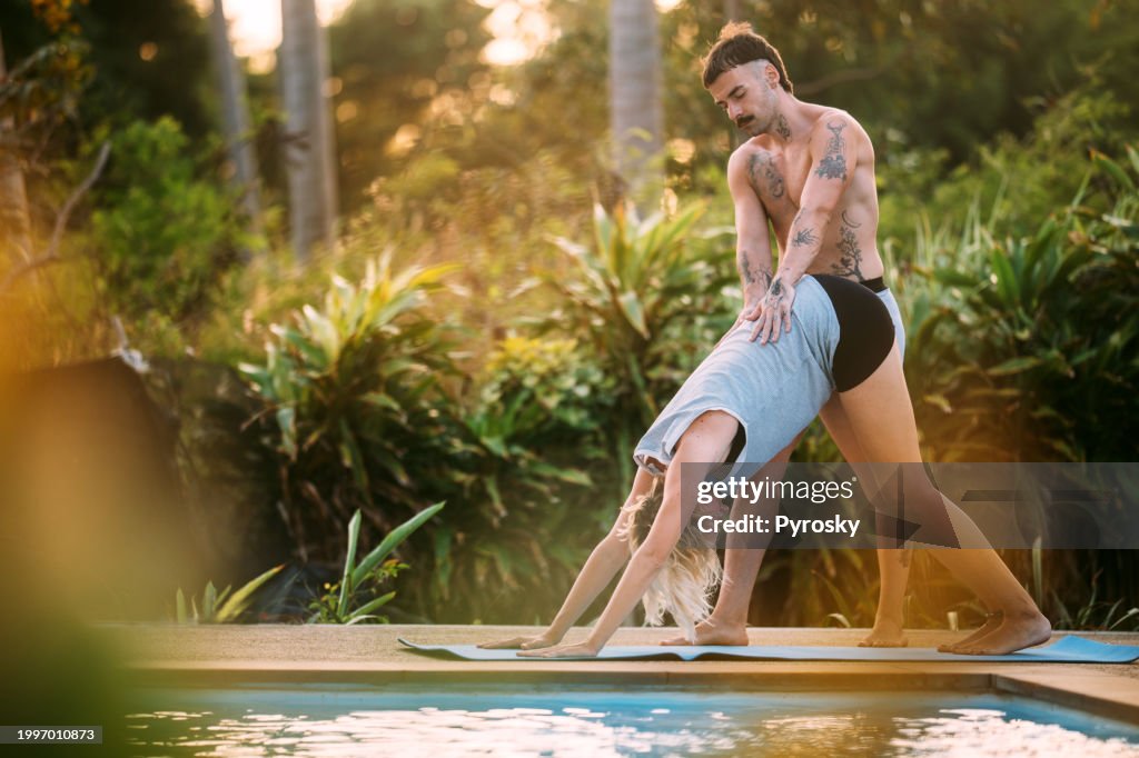 Junger männlicher Yogalehrer unterrichtet das Mädchen in Asanas