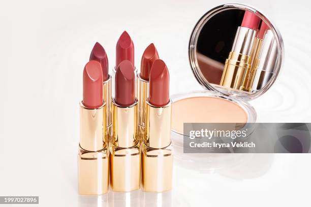 set of red beige pale brown lipstick lip in golden silver glossy tube, face powder blush palette, compact face powder on white color background with reflection. peach fuzz color of the 2024 year. - pale lipstick stockfoto's en -beelden