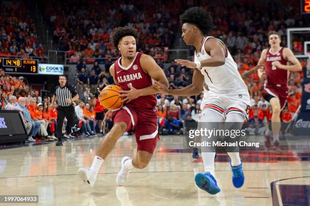 Mark Sears of the Alabama Crimson Tide looks to maneuver the ball by Aden Holloway of the Auburn Tigers at Neville Arena on February 07, 2024 in...