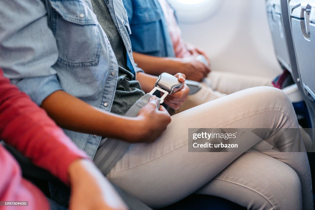 Young Woman Fastening Her Seatbelt In An Airplane