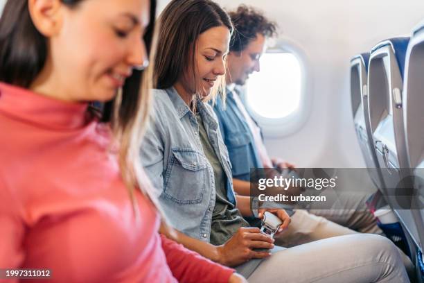 three young people fastening their seatbelt in an airplane - vehicle seat stock pictures, royalty-free photos & images