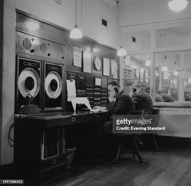 Two men using telephones in the Leicester Square underground station control room, London, November 15th 1956.