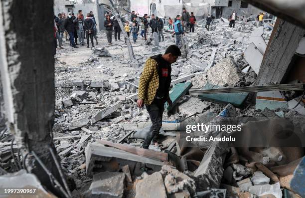Palestinians, including children, collect usable belongings in the heavily damaged buildings after Israeli attacks in Rafah, Gaza on February 12,...