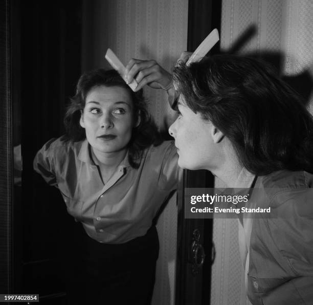 Scottish actress Adrienne Corri combing her hair in a mirror, January 3rd 1957.