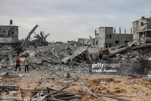 Palestinians, including children, look at the heavily damaged buildings among the rubble after Israeli attacks in Rafah, Gaza on February 12, 2024....