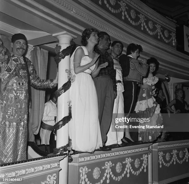 Model and actress Mavis Greenaway stands on a balcony clothed in fancy dress with friends at the Chelsea Arts Ball, Royal Albert Hall, London,...