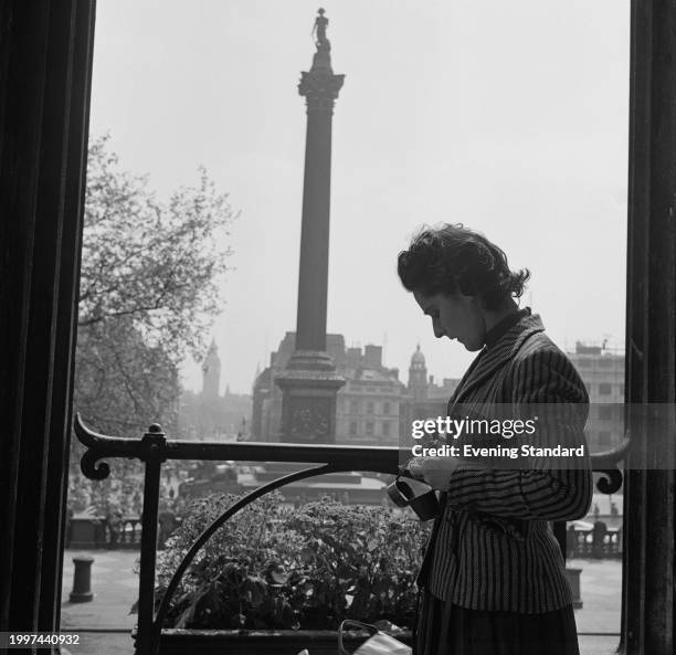 Tourist holds a camera outside the National Gallery with the silhouette of Nelson's Column in the background, London, July 18th 1957.