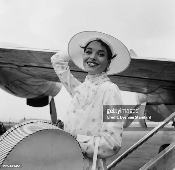 Italian actress Elsa Martinelli holds onto her sun hat, London Airport, July 18th 1957. Martinelli was in London to attend the premiere of her film...