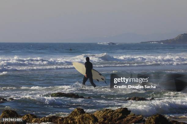 person walks through the ocean water with a surfboard - dana point stock pictures, royalty-free photos & images