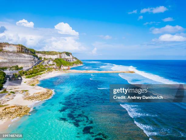 cliffside beach with turquoise waters and white waves on bali. - nusa dua stockfoto's en -beelden