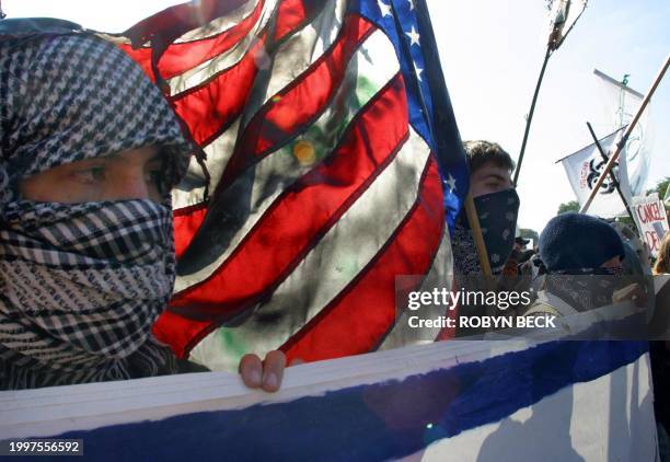 Protestors marched with a burned American flag against IMF and World Bank policies 28 September 2002 in Washington, DC. Thousands gathered to march...