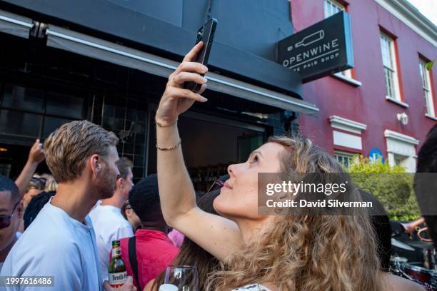 South African woman takes a selfie during a jazz jam session at the Openwine wine bar on January 28, 2024 in trendy downtown Cape Town, South Africa....