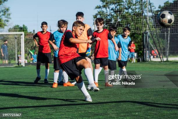 jeunes joueurs de soccer en action lors d’une journée ensoleillée sur le terrain - championnat jeunes photos et images de collection