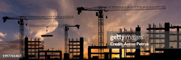 construction site with cranes at sunset - edilizia foto e immagini stock