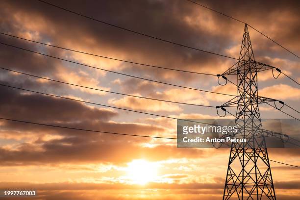 high voltage towers at sunset. power lines - electricity pylons stock pictures, royalty-free photos & images