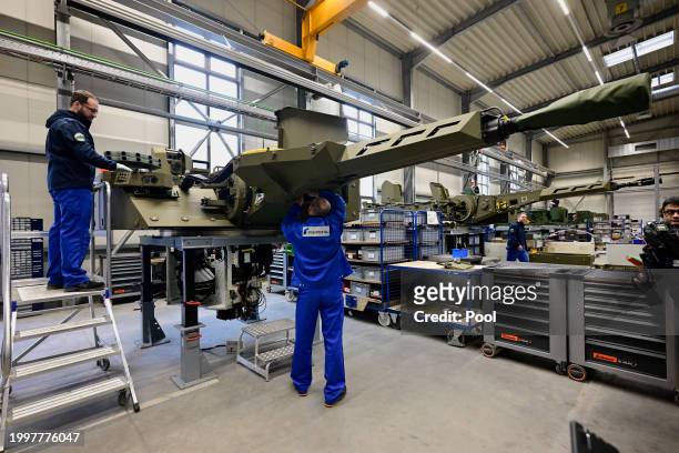 Employees work at a production line as German Chancellor Olaf Scholz and Defence Minister Boris Pistorius attend the groundbreaking ceremony for a...