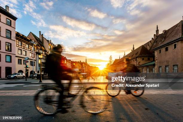 street with cyclists at sunset in strasbourg, france - estrasburgo fotografías e imágenes de stock
