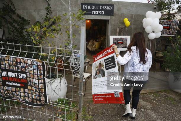 Hagit Matzliah takes off a kidnapped sign from the store where rescued hostage, Fernando Marman, worked in Ramat Hasharon on February 12, 2024 in Tel...
