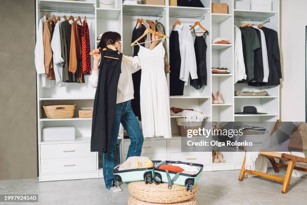 woman packing a suitcase for a trip in the dressing room - kleiderschrank stock-fotos und bilder