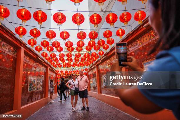 Tourists pose for a photo in front of a temple in Chinatown on Lunar New Years Eve on February 09, 2024 in Bangkok, Thailand. The Chinese diaspora of...