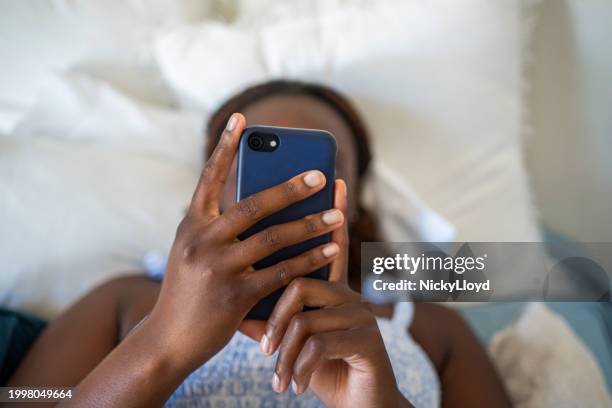teenage girl using a phone while lying on her bed - scrolling stock pictures, royalty-free photos & images