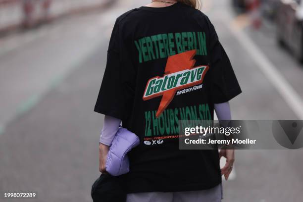 Palina Kozyrava seen wearing Vertere black logo print pattern cotton t-shirt with back print, purple nylon quilted bag, silver / gold rings, on...