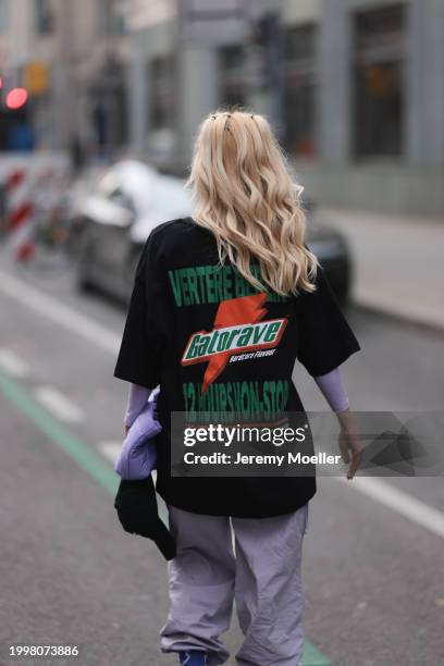 Palina Kozyrava seen wearing Vertere black logo print pattern cotton t-shirt, pastel purple nylon cargo pants, purple nylon quilted bag, on February...