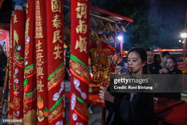 Woman takes a picture of windmill charms with her mobile phone at Sze Yup Kwan Ti temple on Lunar New Year's Eve on February 09, 2024 in Sydney,...