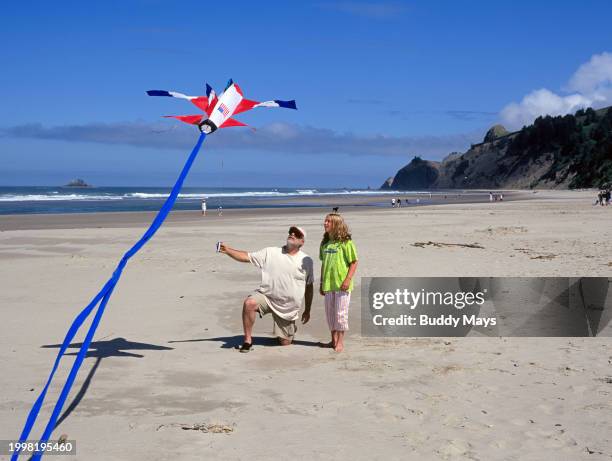 Man teaching a little girl how to fly a large jet plane kite, on a Pacific Ocean beach in Lincoln City, Oregon, 2006. .