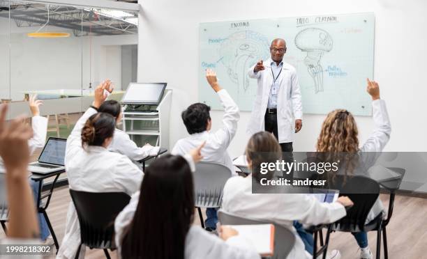 medical students asking question to a teacher in class - medical school stock pictures, royalty-free photos & images