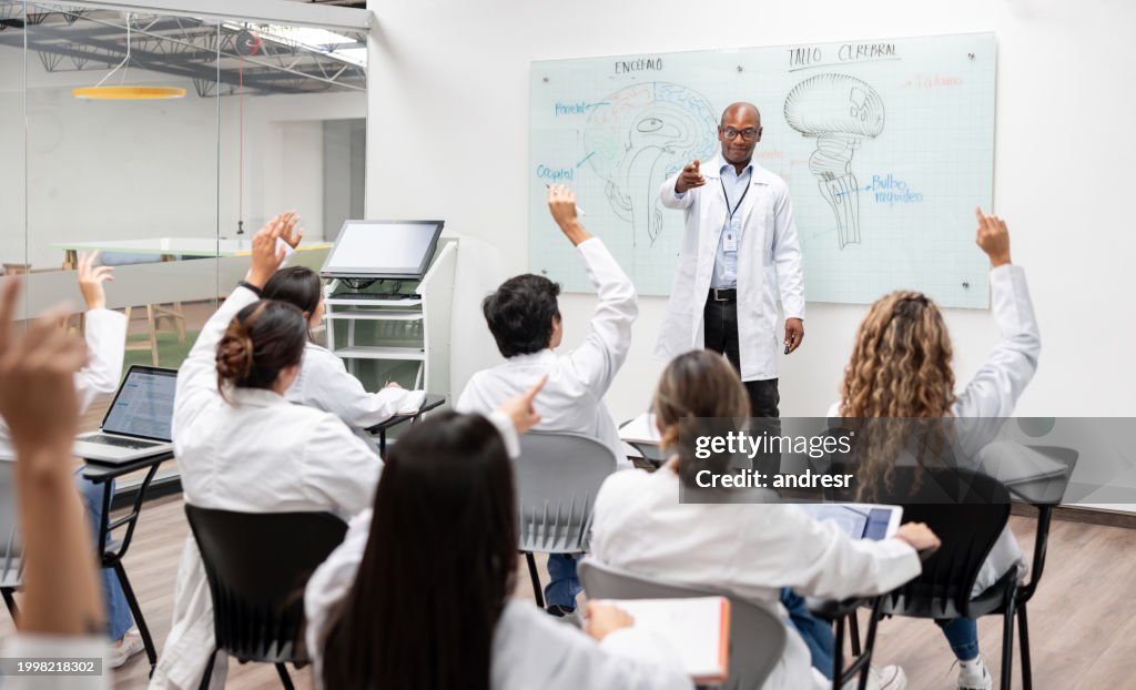 Estudantes de medicina fazendo perguntas a um professor em sala de aula