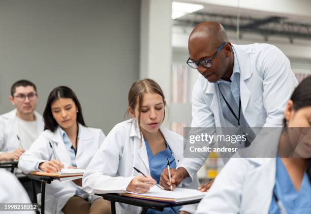 arzt, der an einer medizinischen fakultät unterrichtet und einem studenten im unterricht hilft - medizinische fakultät stock-fotos und bilder