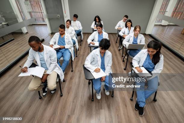 gruppe von medizinstudenten, die eine prüfung in einem klassenzimmer ablegen - medizinische fakultät stock-fotos und bilder