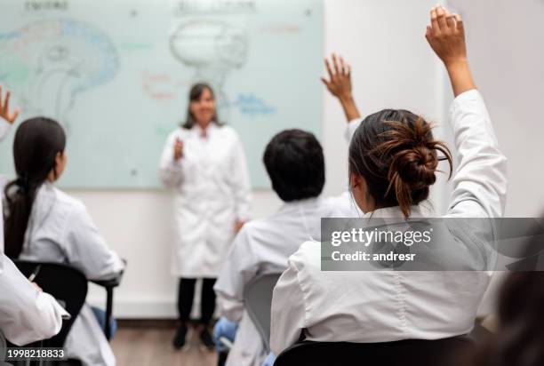 medical students raising their hand to ask questions in class - medical student stock pictures, royalty-free photos & images