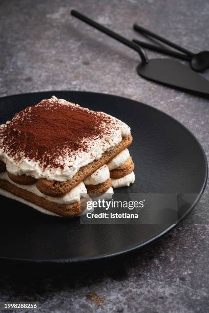 tiramisu cake on black plate - tiramisu stock pictures, royalty-free photos & images