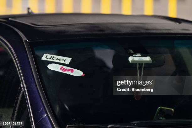 Lyft and Uber signage on a car at San Francisco International Airport in San Francisco, California, US, on Thursday, Feb. 8, 2024. Lyft Inc. Is...