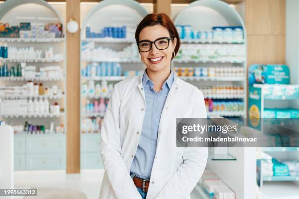 happy female pharmacist at work - apotheker stockfoto's en -beelden