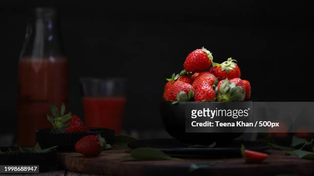 close-up of strawberries and strawberries on table against black background - strawberries stock pictures, royalty-free photos & images