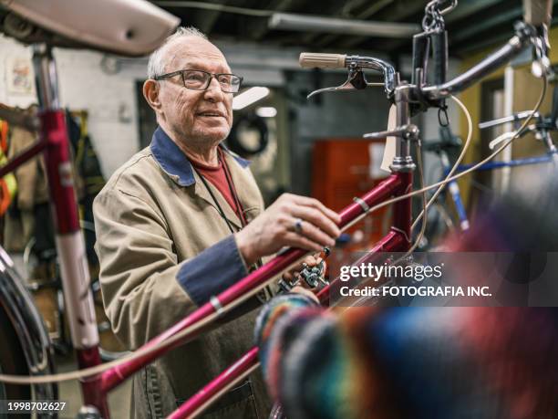 senior man working in his bicycle shop - werkende bejaarden stockfoto's en -beelden