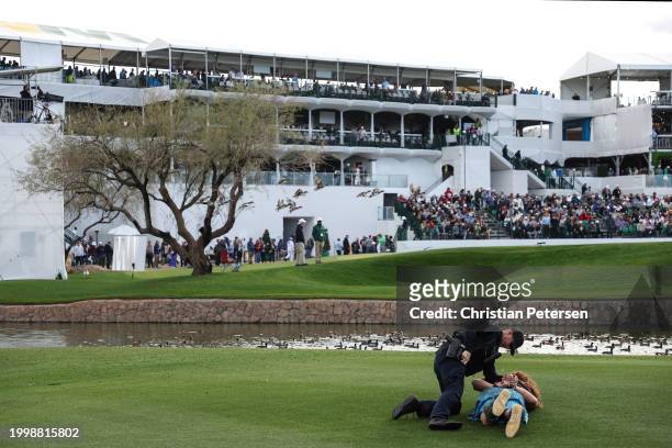 Fan dressed in costume as William Wallace from Braveheart, is apprehended by a police officer after running on the 11th hole during the second round...