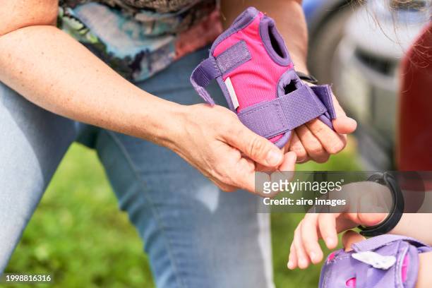 close-up of a mother's hands standing up and adjusting her daughter's protective gloves so she can skate, side view - she can skate stock pictures, royalty-free photos & images