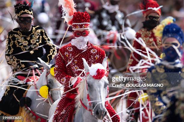 Revelers on horseback take part in a traditional carnival parade in Bonfim, Minas Gerais State, Brazil, on February 12, 2024. Dressed in...