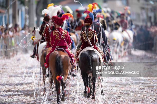 Revelers on horseback take part in a traditional carnival parade in Bonfim, Minas Gerais State, Brazil, on February 12, 2024. Dressed in...