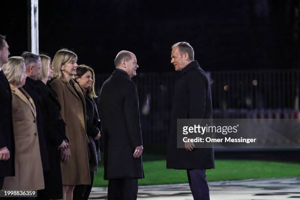 German Chancellor Olaf Scholz and Polish Prime Minister Donald Tusk speak to each other next to the members of the Polish delegation, upon Tusk's...